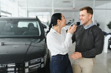 Portrait of a beautiful young couple choosing a new car at a car dealership