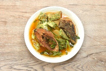 fried snake head fish and egg stuffed climbing wattle in spicy sour soup on plate