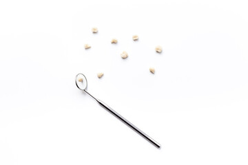 Dental teeth crowns and steel instrument for dental prosthetics, top view. Dentist desk, white background