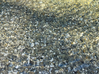 pebbles under transparent water with golden sunlight reflections. calm water surface. natural minimal background. abstract nature background. nature pattern. nature