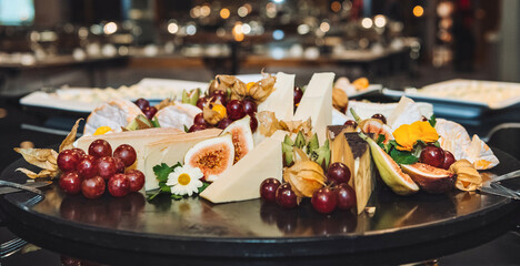 Cheese plate and fruits. Serving on a black platter