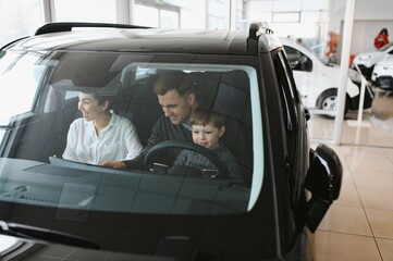 Family in a car dealership. Happy family choosing a new car in a showroom