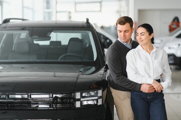 Couple checking new luxury cars at dealership automobile salon