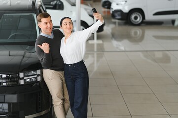 Happy young couple chooses and buying a new car for the family. Visitting the dealership