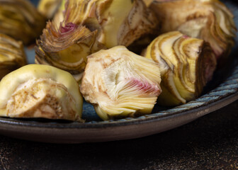 Plate full of fresh raw artichoke hearts ready to cook closeup. Italian cousine ingredient
