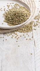 Plate full of dried raw green lentils on white table closeup. Traditional mediterranean legume