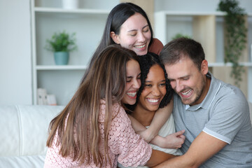 Happy group of best interracial friends hugging at home