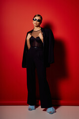 Elegant young woman showcasing stylish fashion against a striking red backdrop