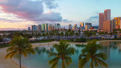 Honolulu skyline and lagoon at sunset. Scenic view of a tropical lagoon with palm trees, sandy...