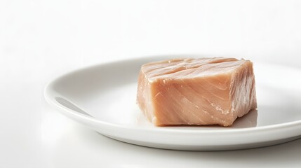 A Single Cube Of Raw Tuna On A White Plate