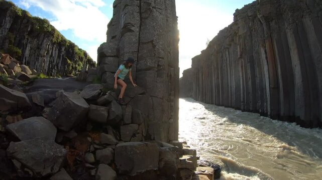 A traveler explores the stunning basalt columns of Stu&eth;lagil Canyon, where Iceland&rsquo;s unique geological formations rise above a rushing river.