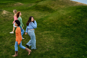 Obraz premium Four stylish women enjoying a lively spring day in a beautiful park setting