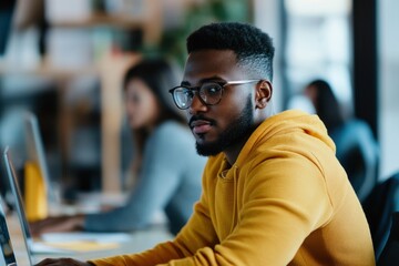 Focused Individual Working on a Laptop in a Modern Office