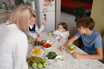 Children sit at a table filled with fresh fruits and snacks while getting ready for school. The scene captures a morning routine filled with healthy food and family interaction.
