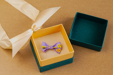 A cheerful ribbon inside a gift box on a light sandy background. Good mood in a gift, a pleasant...