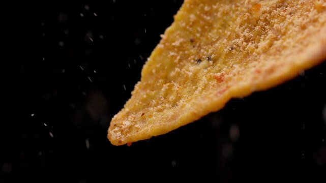 Pouring spicy chili powder on a dorito. Macro close up