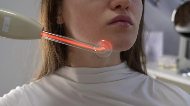 Darsonval facial treatment for skin rejuvenation and acne reduction in a professional beauty salon. High-frequency therapy for skincare, anti-aging, and improved blood circulation