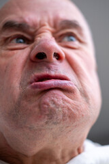 Angry older man with furrowed brow, intense gaze, and pursed lips. Serious senior man looking aggressive and upset, expressing strong emotions, Concept aggression, tension, and confrontation