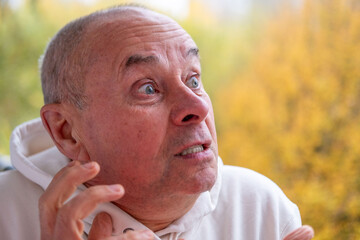 Obraz premium Angry older man with furrowed brow, intense gaze, and pursed lips. Serious senior man looking aggressive and upset, expressing strong emotions, Concept aggression, tension, and confrontation