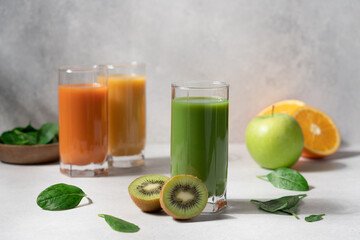 Detox healthy drinks in glasses on light background. Green, yellow and orange smoothie close-up view