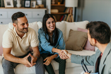 Couple shaking hands with financial advisor during home visit