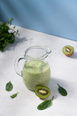Green smoothie in glass jur on blue background. Kiwi spinach vitamin detox healthy drink