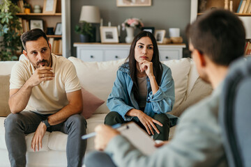 Young couple undergoing marriage counseling with psychologist taking notes
