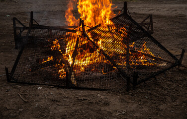 parrilas colocadas al fuego , preparandolas para asar pollos a las brazas 