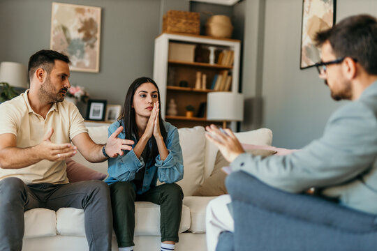 Young couple arguing during therapy session with psychologist