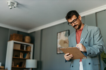 Fototapeta premium Businessman writing notes on clipboard taking notes during meeting