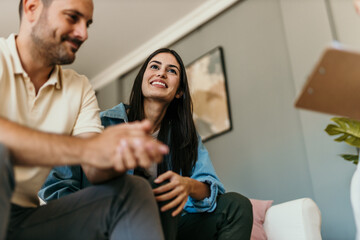 Young couple receiving advice from financial advisor during home visit