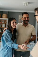 Happy couple shaking hands with real estate agent