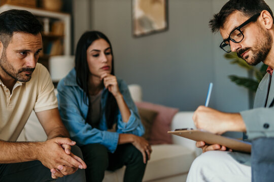 Psychologist taking notes during couples therapy session - Powered by Adobe