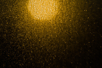 Blurred bokeh light sparkle on golden black background