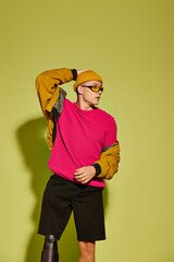 Handsome young man with prosthetic leg showcases trendy fashion in vibrant studio