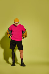 Handsome young man with a prosthetic leg showcases trendy fashion in a vibrant studio