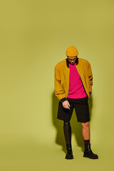 Handsome young man showcasing stylish fashion with a prosthetic leg in a vibrant studio