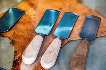 Old and well-used leather cutting blades or paddles on the table of an artisanal tannery workshop.