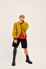 Stylish young man with prosthetic leg showcases modern fashion in studio setting