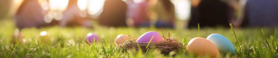 Fototapeta premium Vibrant pastel Easter eggs rest in a nest on lush green grass, surrounded by people enjoying a festive gathering on a sunny spring day