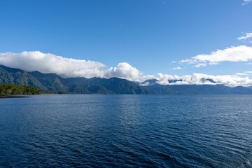 Tranquil lake with mountain range and clouds.