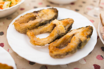Three pieces of fried carp on a white plate