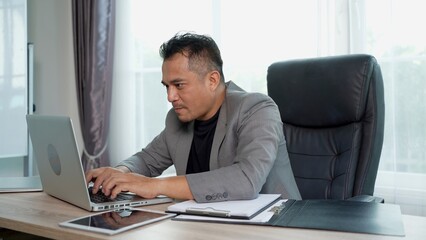 Fototapeta premium Asian Businessman working with Laptop at Office Desk