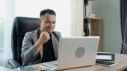 Asian Businessman use laptop and smile with happiness in success