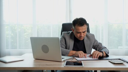 Fototapeta premium Thoughtful Asian Businessman working with document on Desk at office