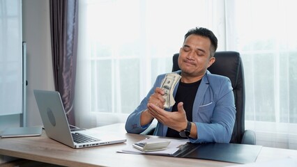 Fototapeta premium Happily Businessman in suit Counting Money on desk in Office