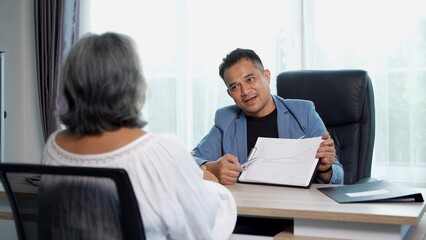 Businessman presents company growth chart to gray-hair woman during discussion