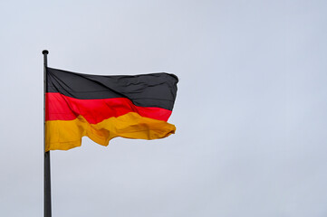 Flag of Germany waving against sky on flagpole