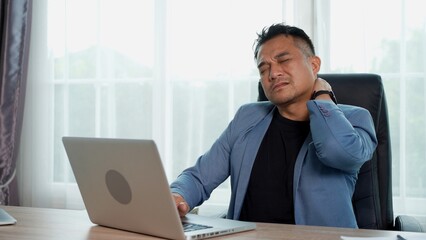 Businessman working on laptop, feeling pain neck from hard work, office syndrome