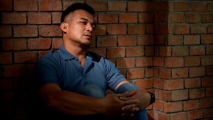 Sadness Man sits leaning Against a Brick Wall with Expressing Distress